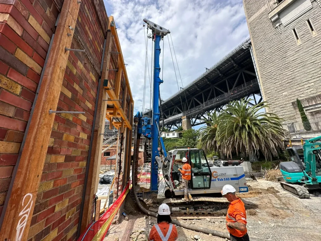 Millent Civil Works piling rig installing piles beside a retained heritage brick wall beneath the Sydney Harbour Bridge