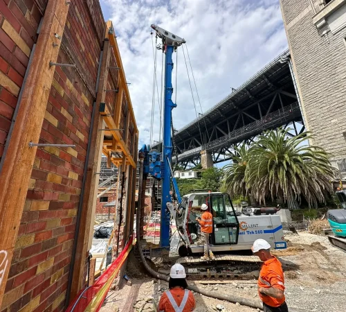 Millent Civil Works piling rig installing piles beside a retained heritage brick wall beneath the Sydney Harbour Bridge