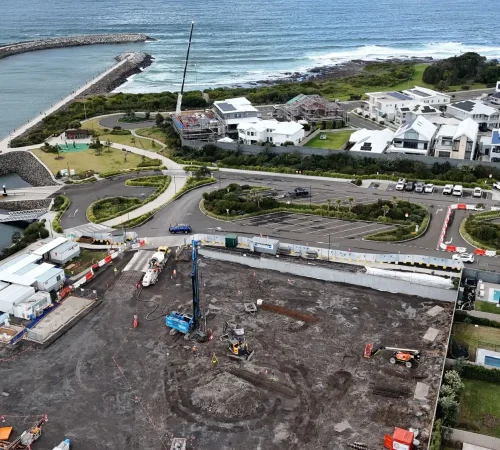 Overhead view of the Shell Cove piling site beside the marina breakwater, with the rig, concrete truck and site sheds